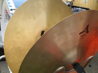 Zwei Schlagzeugbecken liegen nebeneinander. Eines ist golden und das andere hat eine helle Oberfläche.