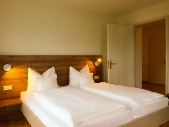 Ein gemütliches Schlafzimmer mit zwei Einzelbetten und modernem Holzdesign. Die Wände sind hell gestrichen und der Raum wirkt einladend und hell.