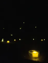 Ein dunkler Raum mit vielen kleinen, leuchtenden Kerzen. Die Kerzen erzeugen eine warme, stimmungsvolle Atmosphäre.