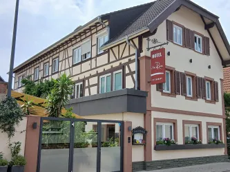Ein charmantes Hotelgebäude mit einem traditionellen Fachwerkstil. Es hat eine einladende Fassade und bepflanzte Fensterbänke.