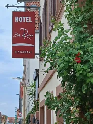 Ein Schild mit der Aufschrift "Hotel zum Riesen" hängt an der Wand eines Gebäudes. Umgeben von grünen Pflanzen, vermittelt es eine einladende Atmosphäre.