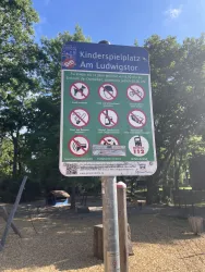 Ein Schild mit Regeln für den Kinderspielplatz am Ludwigstor. Es zeigt verschiedene Verbotssymbole und stellt sicher, dass die Sicherheit der Kinder gewährleistet ist.