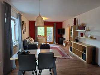 Ein modernes Wohn-Esszimmer mit  einer gemütlichen Couch. Ein schöner Blick auf die Terrasse und den Garten.