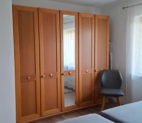 Ein moderner Kleiderschrank aus Holz mit einem Spiegel.