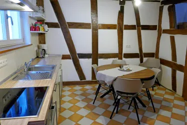 Eine gemütliche Küche mit Holzdecken und einem runden Tisch. Der Boden ist mit eleganten, schachbrettartigen Fliesen gestaltet.