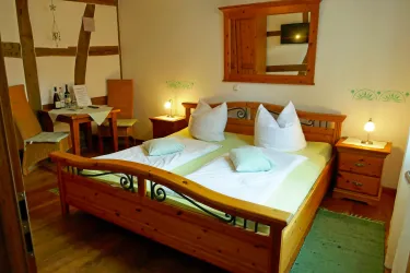 Ein gemütliches Schlafzimmer mit einem Doppelbett und zwei Nachttischen. Der Raum hat Holzmöbel und eine kleine Essecke.