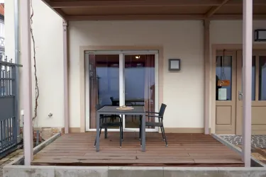 Ein gemütlicher Balkon mit einem Tisch und zwei Stühlen. Die Wände sind hell und die Fenster bieten einen Blick nach draußen.