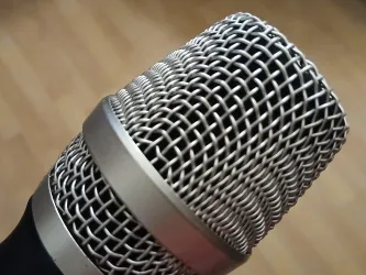 Ein Mikrofon mit einem silbernen Gitter und einem schwarzen Griff. Es ist nah aufgenommen und zeigt die Details des Mikrofons.