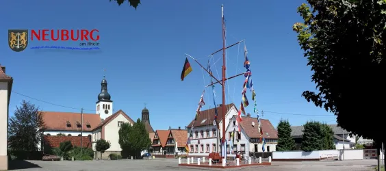 Ein historisches Gebäude mit Fachwerk und ein modernes Haus mit roten Dächern. Die Szene zeigt eine ruhige Straße im Ortszentrum.