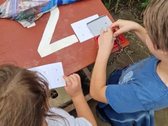 Zwei Kinder stempeln ihre Stempelkarte im Maislabyrinth