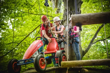 Mädchen und Kletterguide halten ein Kettcar fest auf Parcours im Abenteuerpark Kandel