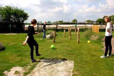 Eine Frau kickt einen Fußball durch den Parcours, eine zweite schaut zu.