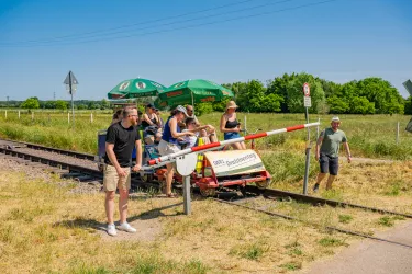 Eine voll besetzte Draisine hält an einer Schranke