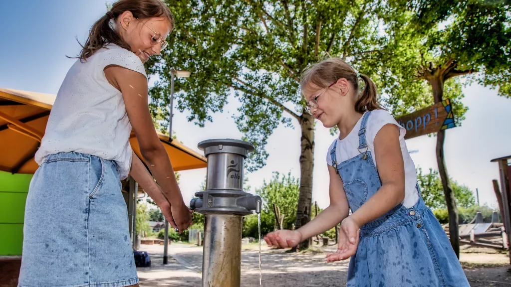Zwei Mädchen planschen an einem Brunnen an der Alla-Hopp-Anlage
