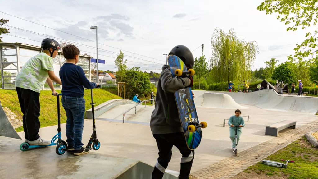 Kinder mit Scootern auf einer Skateanlage