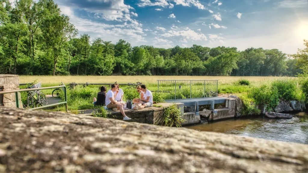 Eine Gruppe von fünf Freunden sitzt am Teilungswehr und picknickt