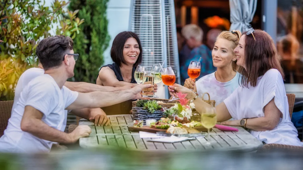 Eine Gruppe von Freunden sitzt an einem reich gedeckten Tisch und prostet sich zu
