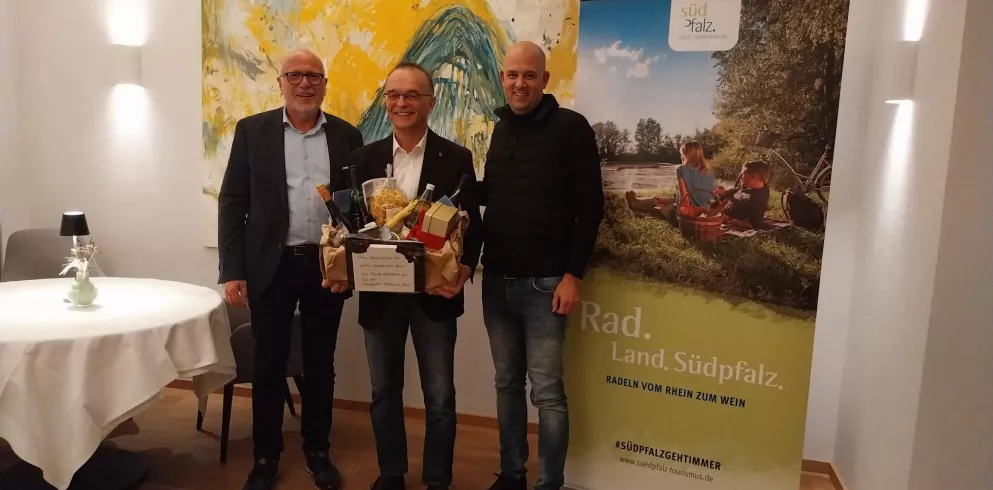 Volker Poß, Dr. Fritz Brechtel und Martin Brandl. Dr. Brechtel hält einen Präsentkorb in beiden Händen.