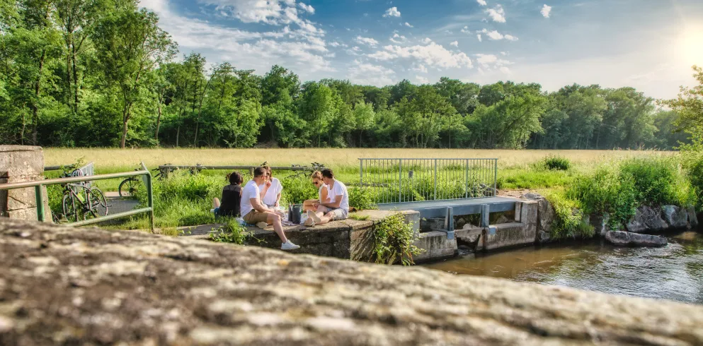 Eine Gruppe von fünf Freunden sitzt am Teilungswehr und picknickt