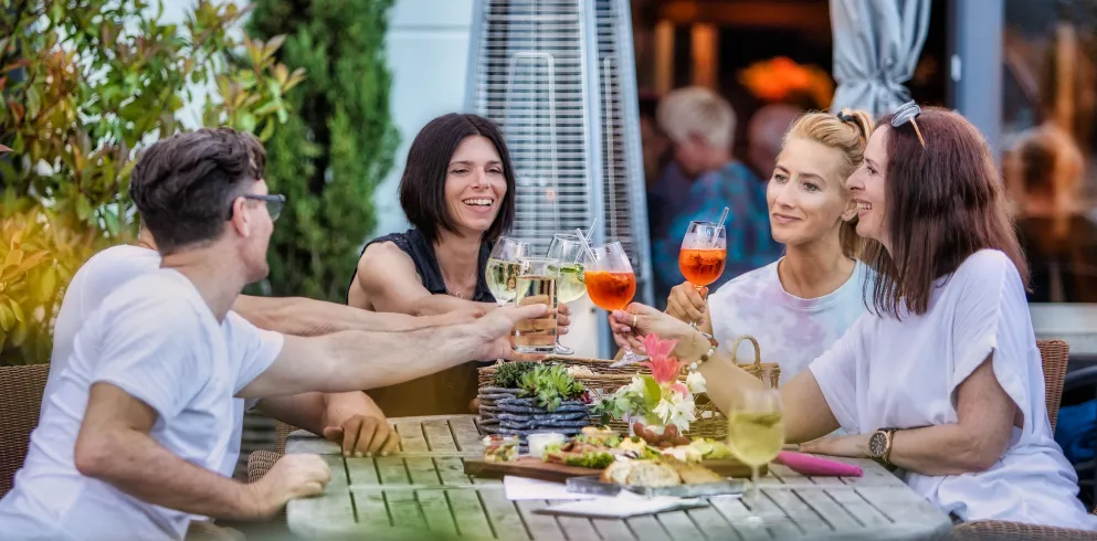 Eine Gruppe von Freunden sitzt an einem reich gedeckten Tisch und prostet sich zu