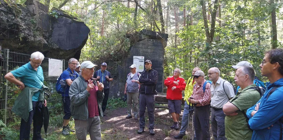 Eine Gruppe Wanderer vor den Ruinen eines Bunkers im Bienwald