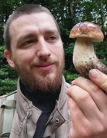 Ein Mann hält einen Pilz in der Hand