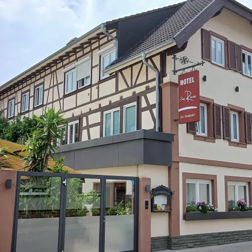 Ein charmantes Hotelgebäude mit einem traditionellen Fachwerkstil. Es hat eine einladende Fassade und bepflanzte Fensterbänke.