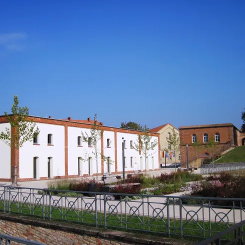 Ein modernes Gebäude mit weißen Wänden und Bäumen umgeben. Der Himmel ist klar und blau.