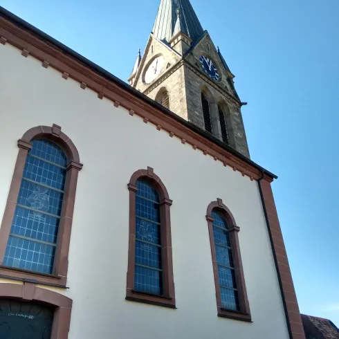 Eine Kirche mit einem hohen Turm und schönen Fenstern. Der Himmel ist klar und blau.