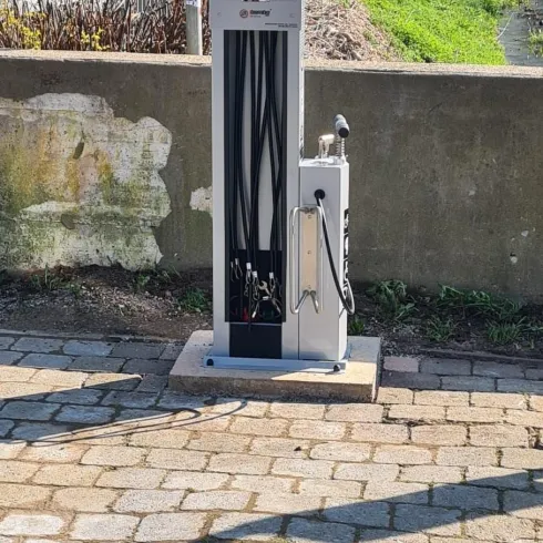 Eine Station zur Wartung von Fahrrädern steht an einem Gehweg. Sie bietet verschiedene Werkzeuge und Möglichkeiten zur Reparatur.