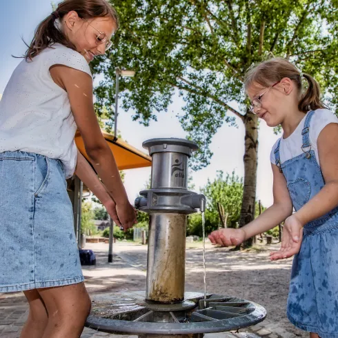 Zwei Mädchen planschen an einem Brunnen an der Alla-Hopp-Anlage