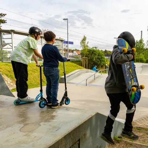 Kinder mit Scootern auf einer Skateanlage