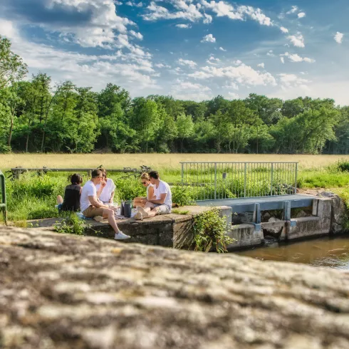 Eine Gruppe von fünf Freunden sitzt am Teilungswehr und picknickt
